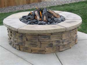 round fire pit with fire burning grass in background