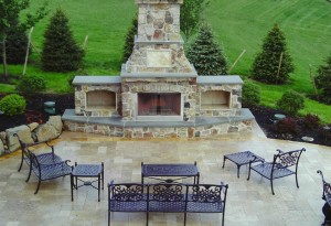 large out door fireplace with three fireboxes and hearths. sets of metal chairs arranged out in front of it