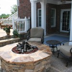 firepit on patio with two chairs and table by it and house with doubledoors in the background