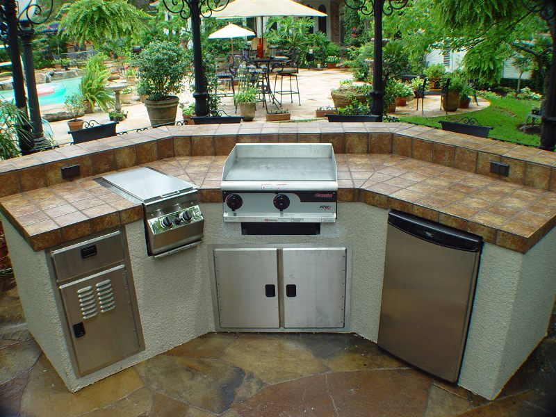 trenton island style outdoor kitchen with appliances overlooking plants and a pool