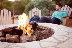 man and child sitting by firepit